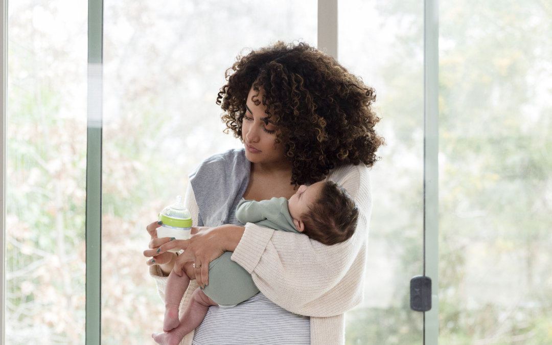 black mother feeds newborn baby formula from a bottle